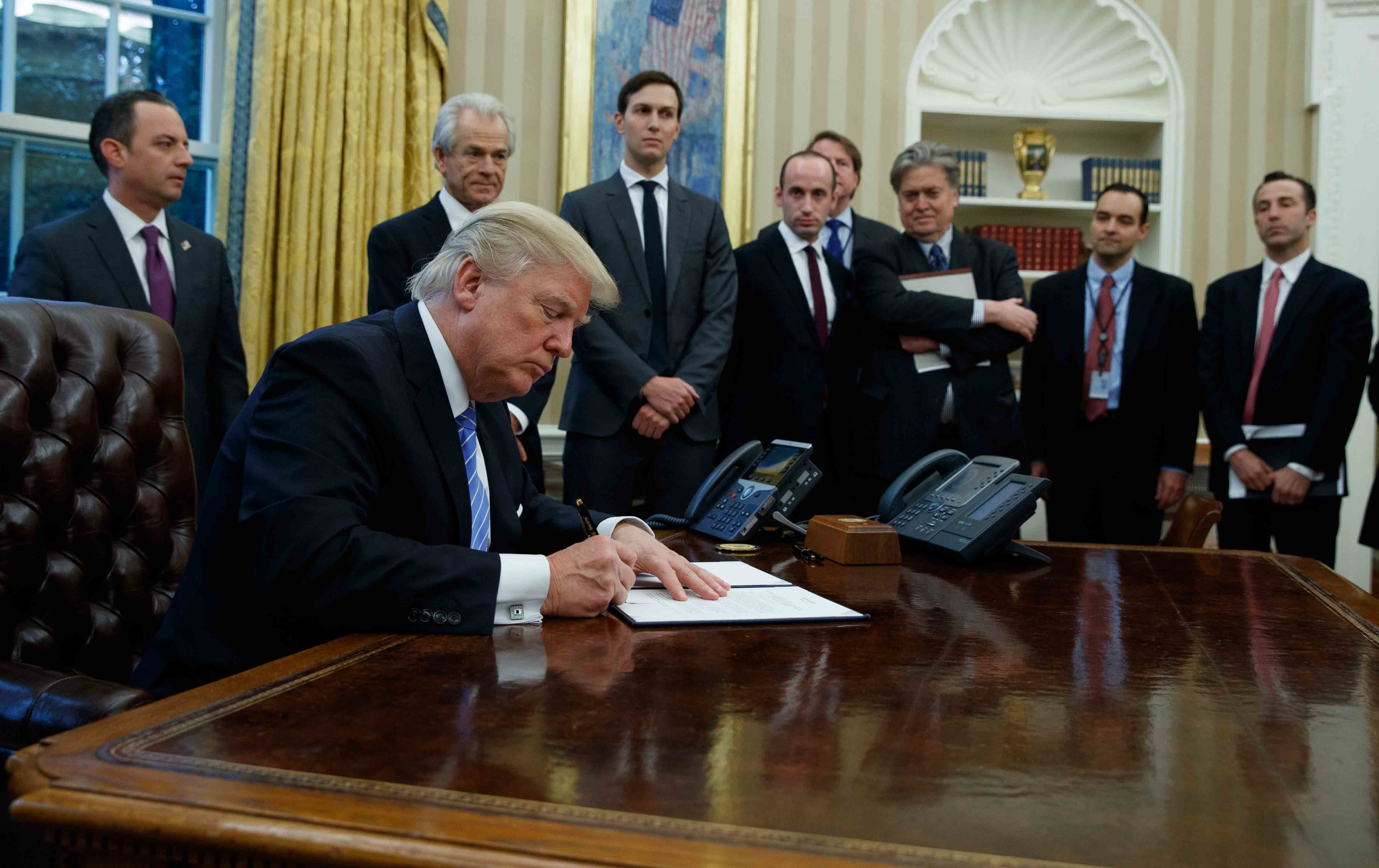 Accompanied by a line-up of his white male advisers, President Donald Trump signed a