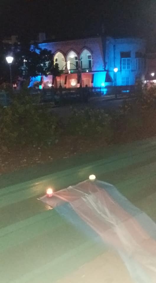 During the ceremony of Trans remembrance, the Trans Pride flag was displayed in front of Barbados' House of Assembly, uplit in the country's blue and yellow national colours to celebrate the country's independence. The flag was anchored by four candles, each one representing 100 Trans and Gender Non-conforming persons who were lost to transphobia and gender based violence between 2017 and 2018. (Photo courtesy of Alexa Hoffman)