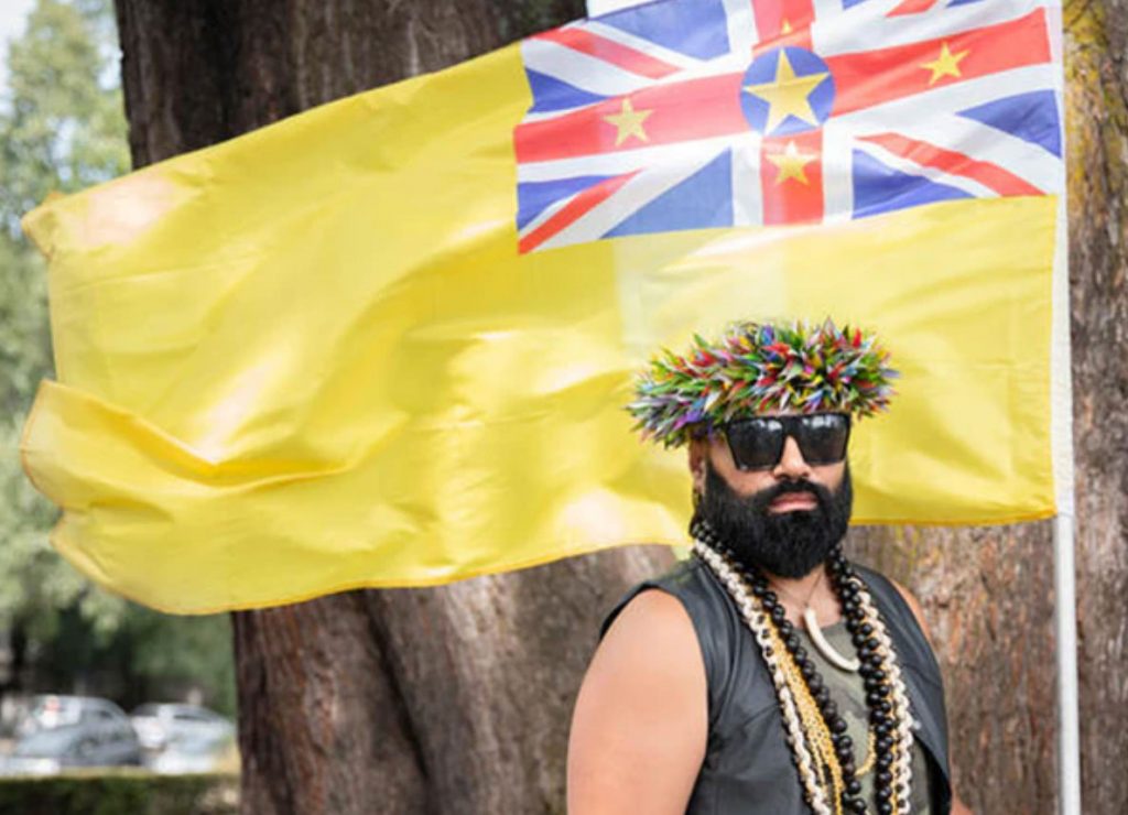 Pride marcher in New Zealand poses with the flag of the tiny island nation Niue. (Claire-Eastham-Farrelly photo courtesy of NZTV)