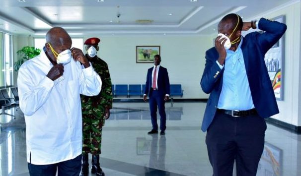 Ugandan President Yoweri Museveni (left) tries on a face mask to protect him against Covid-19.