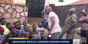 Police and army flanked by Kyengera town council mayor Haji Abdu Kiyimba beat the shelter residents during March 29 raid. (Screen shot from BBSTV video)