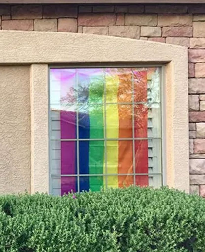 Rainbow flag hanging in a window.