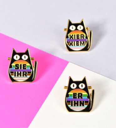 Lovonova pins displaying German pronouns -- Sie Ihr (She Her), Er Ihn (He Him) and the non-binary Xier Xiem."