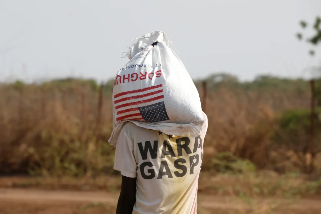 A man carries a bag of U.S. food aid at the Kakuma refugee camp in northern Kenya in 2018. (Baz Ratner photo courtesy of Reuters / Context)