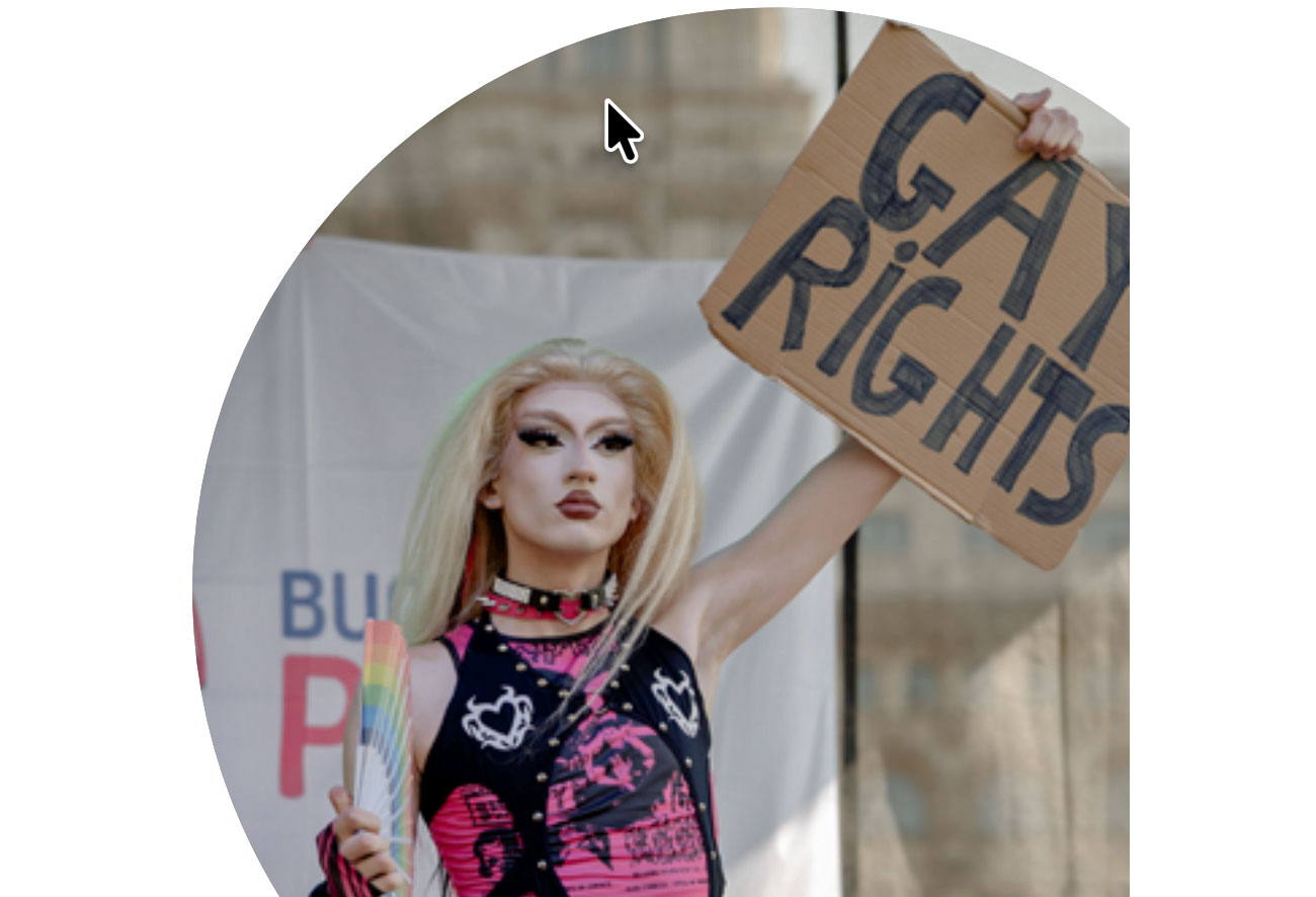 A drag queen raising a placard saying “Gay Rights” in Bucharest Pride, with the Romanian Palace of Parliament seen behind. (Claudiu Popescu photo from Outright's report "Queering Democracy: The Global Elections in 2024 and How LGBTIQ People Fared")
